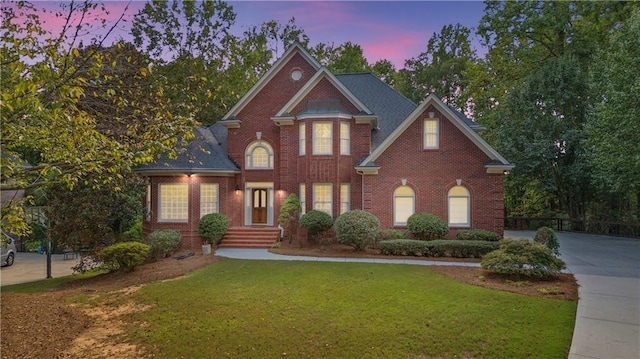 view of front of house featuring a lawn, brick siding, and driveway