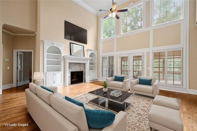 living area with baseboards, wood finished floors, and ornamental molding