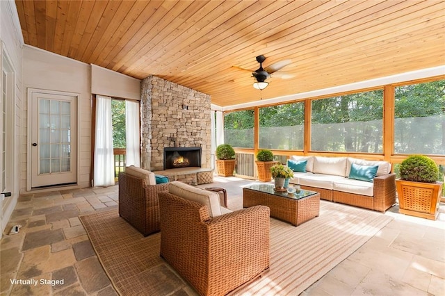 sunroom featuring a stone fireplace, lofted ceiling, wood ceiling, and ceiling fan