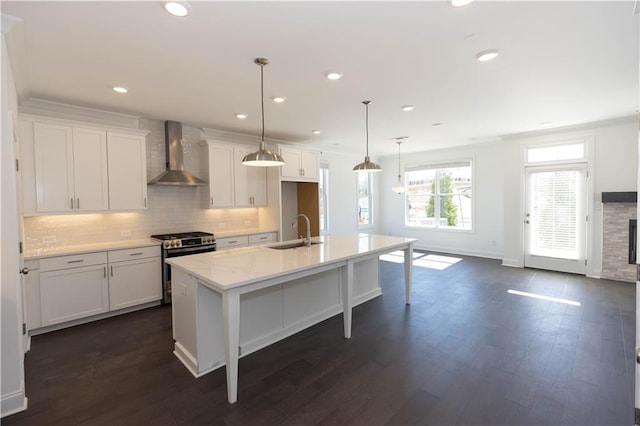 kitchen featuring sink, a kitchen island with sink, white cabinetry, gas stove, and wall chimney exhaust hood