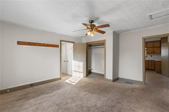 unfurnished bedroom with ceiling fan, light carpet, a textured ceiling, and a closet