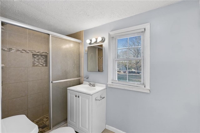 bathroom featuring vanity, a textured ceiling, toilet, and walk in shower