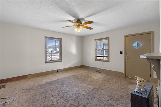 entryway featuring ceiling fan, plenty of natural light, carpet floors, and a textured ceiling