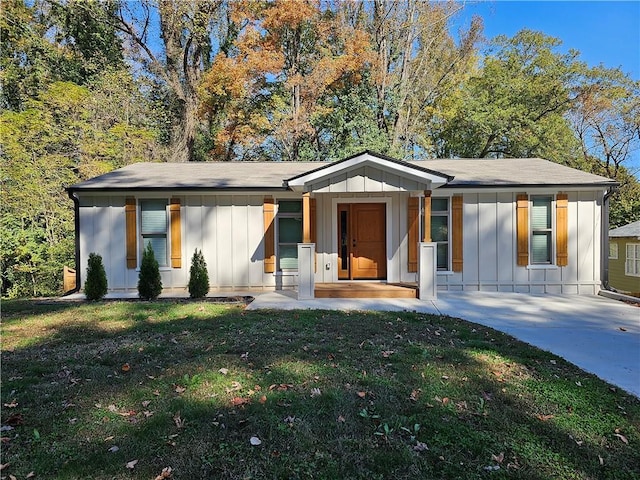 view of front of home with board and batten siding, driveway, and a front lawn