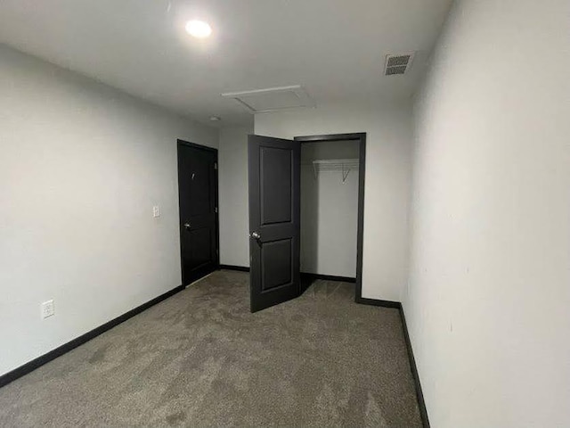 unfurnished bedroom with a closet, attic access, baseboards, carpet flooring, and visible vents