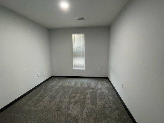 carpeted spare room featuring baseboards and visible vents