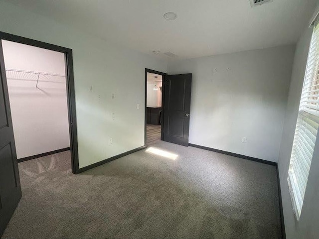 unfurnished bedroom with a spacious closet, baseboards, carpet floors, and a closet