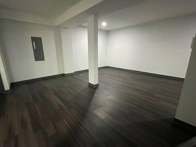 finished basement with baseboards, dark wood-type flooring, and electric panel