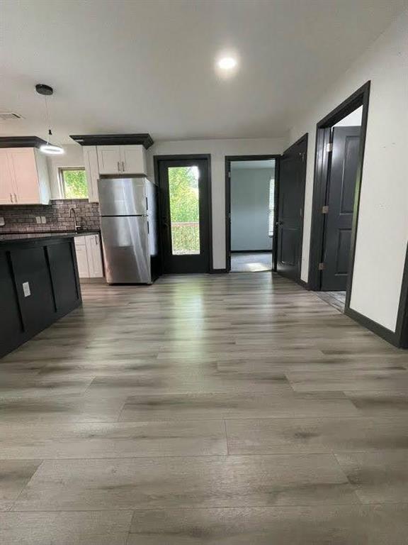 interior space with white cabinets, light wood finished floors, dark countertops, plenty of natural light, and freestanding refrigerator