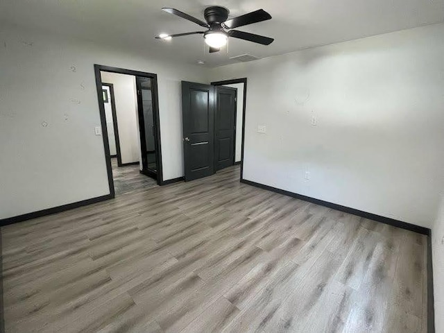 unfurnished room featuring light wood-style flooring, visible vents, baseboards, and ceiling fan