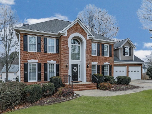 colonial inspired home with a garage and a front lawn