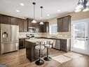 kitchen featuring hanging light fixtures, a kitchen island, dark brown cabinetry, and stainless steel fridge with ice dispenser