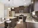 kitchen with dark brown cabinetry, a kitchen bar, a center island, hanging light fixtures, and stainless steel appliances