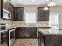 kitchen with stainless steel appliances, light wood-type flooring, pendant lighting, and dark brown cabinetry