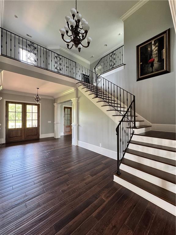 311 Langston Rd SE, Calhoun, GA 30701 - stairs featuring a chandelier, ornamental molding, wood finished floors, baseboards, and decorative columns
