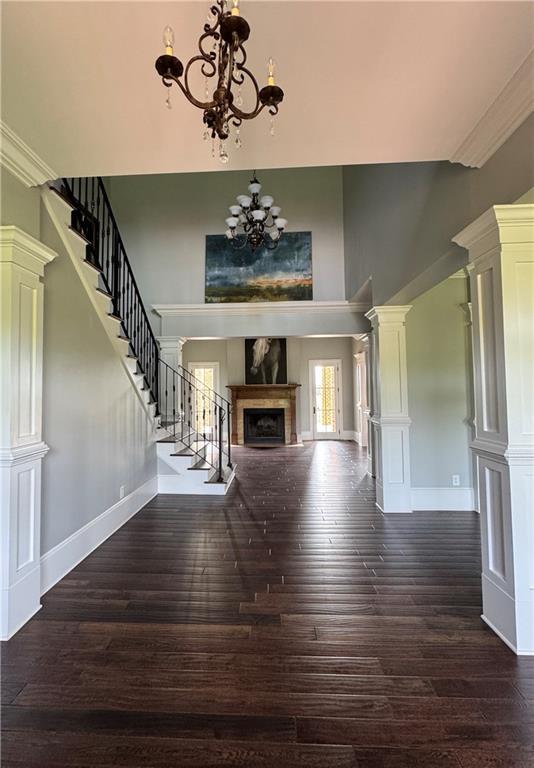 311 Langston Rd SE, Calhoun, GA 30701 - unfurnished living room featuring a high ceiling, a chandelier, dark wood-style floors, a fireplace, and stairway
