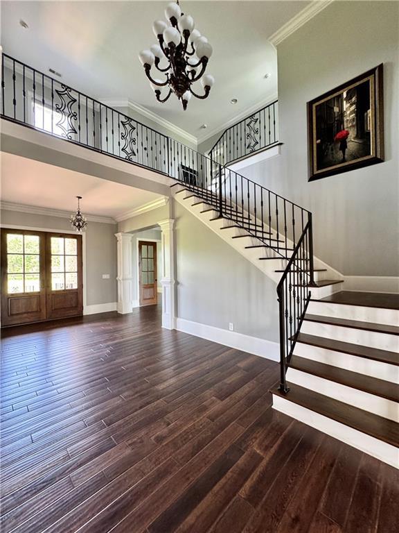 311 Langston Rd SE, Calhoun, GA 30701 - stairs featuring a chandelier, ornamental molding, wood finished floors, baseboards, and a towering ceiling