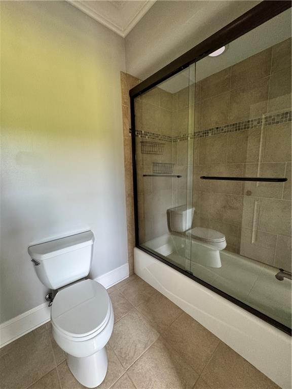 311 Langston Rd SE, Calhoun, GA 30701 - bathroom with toilet, shower / bath combination with glass door, ornamental molding, baseboards, and tile patterned flooring