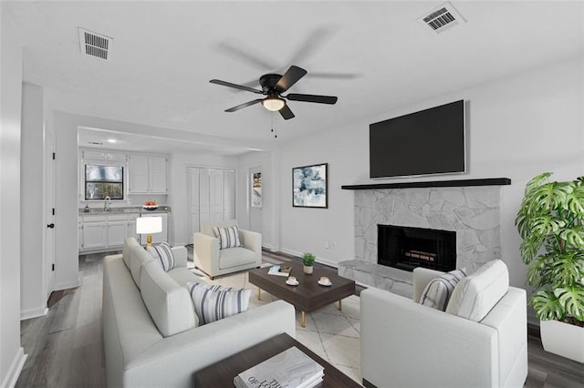 2571 Hamill Dr, Buford, GA 30519 - living area with baseboards, a fireplace with raised hearth, ceiling fan, and dark wood-type flooring