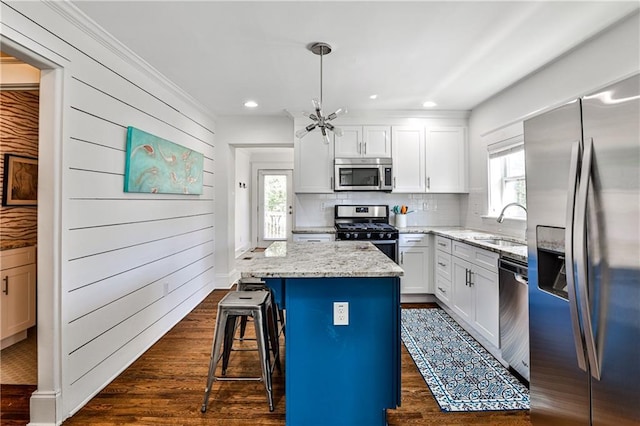 kitchen featuring a kitchen bar, a sink, a kitchen island, dark wood-style floors, and stainless steel appliances