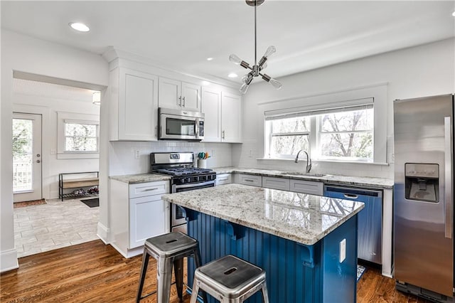 kitchen featuring a sink, dark wood-style floors, a center island, appliances with stainless steel finishes, and decorative backsplash