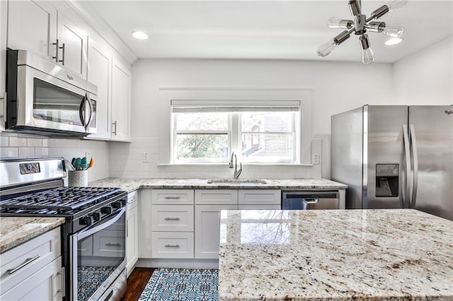 kitchen featuring a sink, decorative backsplash, white cabinetry, and stainless steel appliances