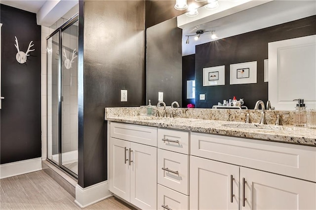 full bath featuring a stall shower, a sink, double vanity, baseboards, and ceiling fan