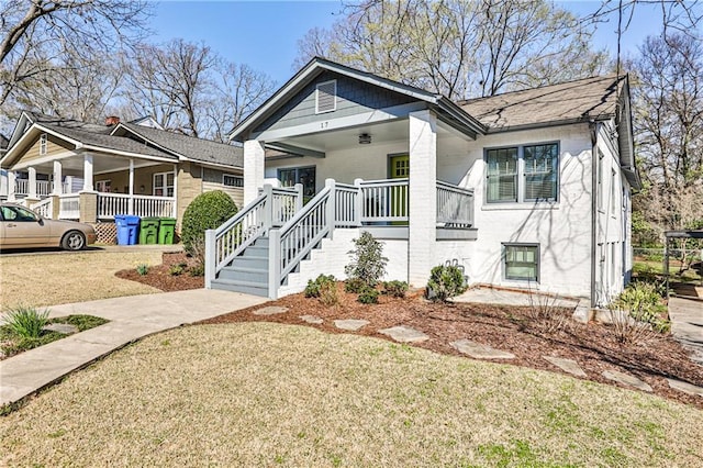 bungalow-style house with a porch, stairs, and a front yard