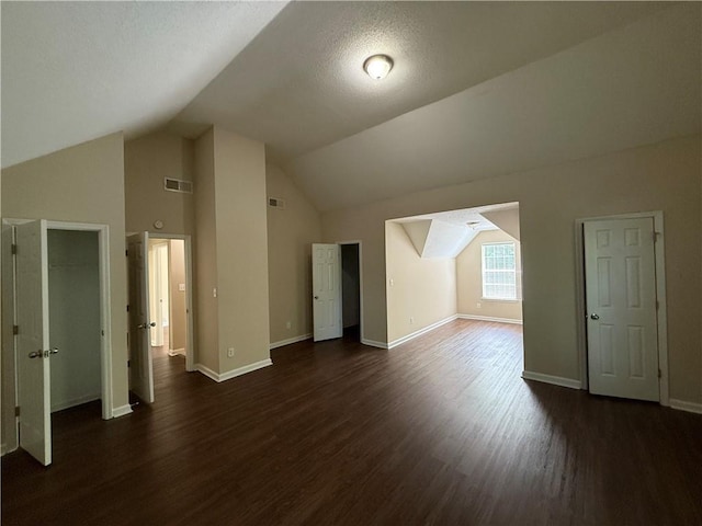 additional living space featuring baseboards, lofted ceiling, dark wood-style floors, and visible vents