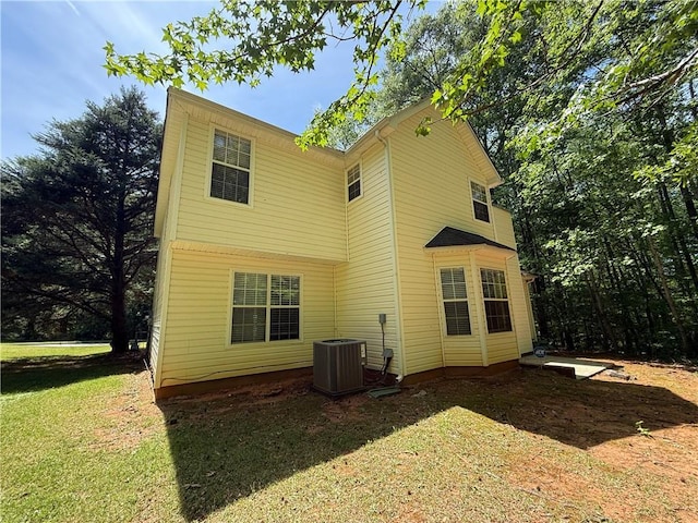 back of property with central air condition unit and a yard