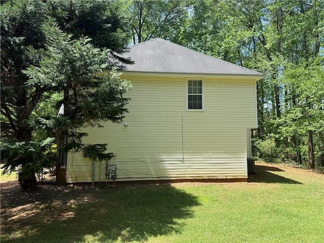 view of home's exterior with a yard, central AC, and roof with shingles