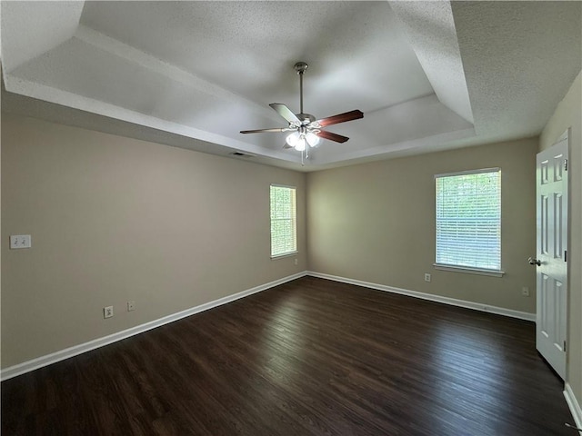 interior space with ceiling fan, a textured ceiling, baseboards, a tray ceiling, and dark wood-style floors