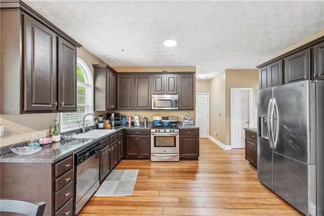 642 Towering Pine Trl, Lawrenceville, GA 30045 - kitchen with appliances with stainless steel finishes, a sink, dark brown cabinets, light wood-type flooring, and a textured ceiling