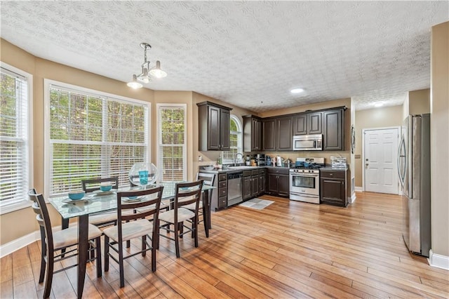 642 Towering Pine Trl, Lawrenceville, GA 30045 - kitchen with appliances with stainless steel finishes, a sink, baseboards, dark brown cabinets, and a textured ceiling
