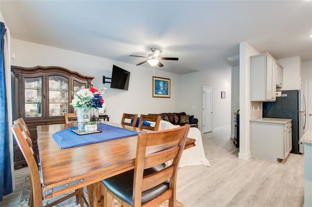 dining space with light wood-type flooring, ceiling fan, and baseboards