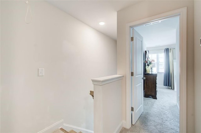 corridor featuring baseboards, light colored carpet, and an upstairs landing