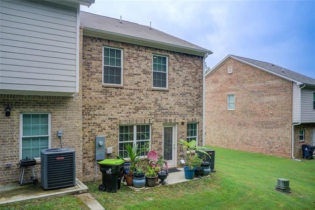 rear view of property with brick siding, a lawn, and central air condition unit