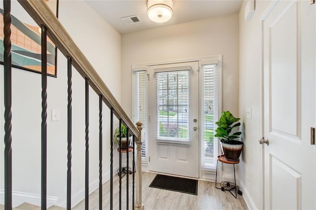 entrance foyer with stairway, light wood-type flooring, visible vents, and baseboards