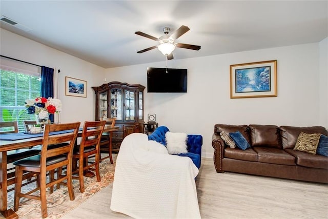 living area with light wood-style floors, ceiling fan, and visible vents