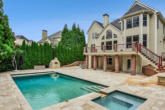 rear view of property with a pool with hot tub and a patio area