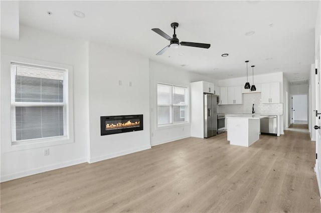 1500 Murphy Ave SW, Atlanta, GA 30310 - unfurnished living room featuring light wood-type flooring, ceiling fan, a glass covered fireplace, baseboards, and a sink