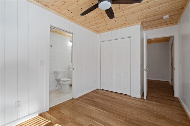 unfurnished bedroom with wood finished floors, a closet, connected bathroom, wood ceiling, and ceiling fan
