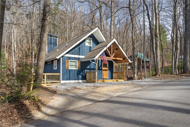 chalet / cabin with a chimney, roof with shingles, and board and batten siding