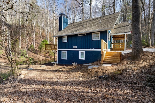 rear view of property featuring stairway, a chimney, board and batten siding, covered porch, and roof with shingles