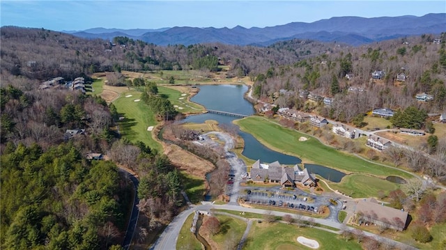 birds eye view of property with a forest view, a water and mountain view, and view of golf course