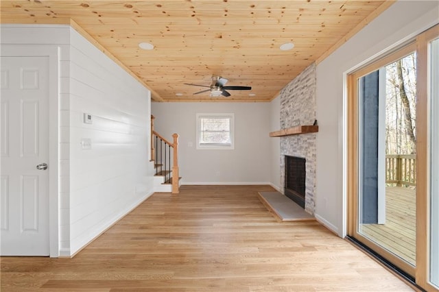 unfurnished living room featuring wood ceiling, a fireplace, stairs, and light wood finished floors