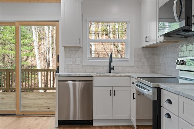 kitchen with white cabinets, a sink, decorative backsplash, appliances with stainless steel finishes, and ornamental molding