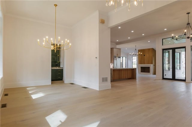 interior space featuring a chandelier, light hardwood / wood-style floors, ornamental molding, and french doors