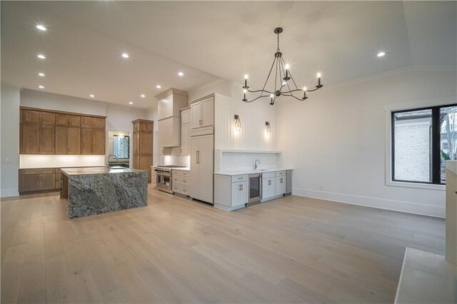 kitchen with french doors, hanging light fixtures, light hardwood / wood-style floors, a spacious island, and custom exhaust hood