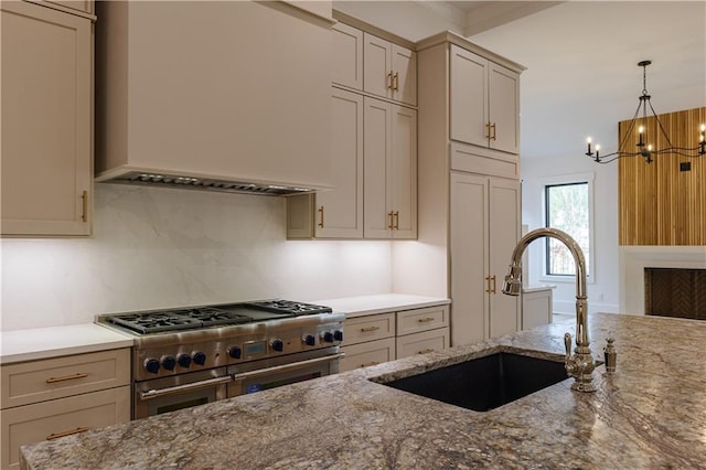 kitchen featuring light stone countertops, custom range hood, sink, decorative light fixtures, and double oven range